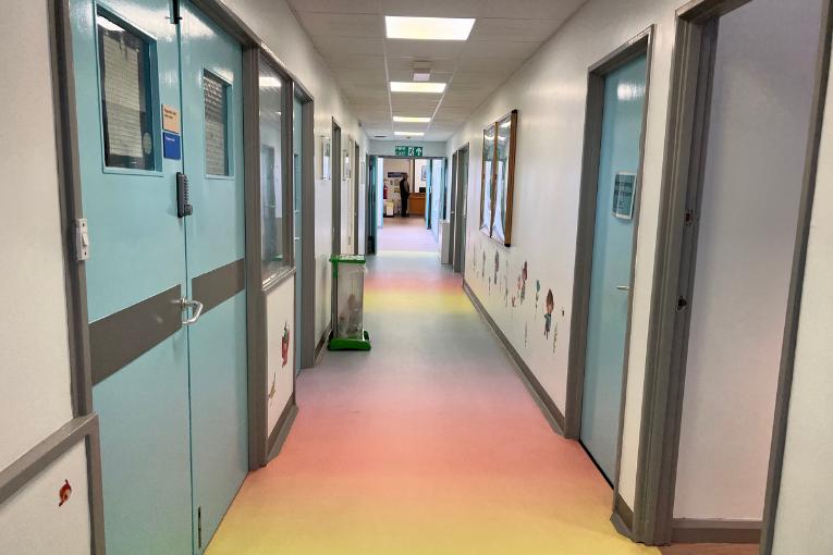 Corridor of children's unit with rainbow flooring and blue doors